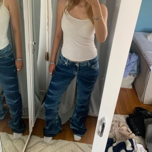 Blå veckade low-waist bootcut jeans Weekday - Säljer ett par blå lågmidjade bootcut jeans från weekday med klassisk femficksdesign och veckat mönster. Endast testade med prislapp kvar. Köpta för 700kr.