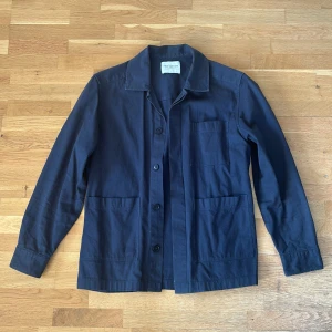 Mörkblå overshirt från These Glory Days - Stilren mörkblå overshirt med tre stora fickor framtill och knäppning med svarta knappar. Klassisk krage och rak passform, perfekt att bära över en t-shirt. Tillverkad i bomull för en bekväm känsla.