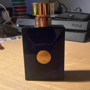 Versace Pour Homme Dylan Blue Eau de Toilette T.      O.     M - Mörkblå fyrkantig parfymflaska från Versace med guldig detalj och lock. Flaskan har Versaces ikoniska Medusa-symbol framtill och ett elegant, lyxigt utseende. Passar dig som gillar exklusiva dofter och snygg design. Köpt för runt 500kr. Perfekt till sommaren. Priset ej hugget i sten. Boxen följs osså med. Svårt o se hur mycke det är kvar.