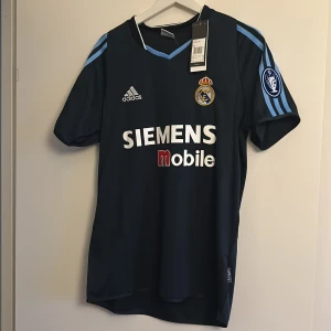 Real Madrid (Raúl 7) 03/04 away shirt - Säljer en helt oanvänd retro mörkblå Real Madrid bortatröja . Stl är S men jag skulle säga att den passar M bättre om man vill ha en mer slim fit. Priset kan diskuteras vid snabb affär✅Perfekt att använda nu till sommaren!