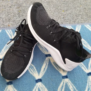 Svarta Nike sneakers med vit sula - Säljer ett par svarta Nike sneakers med vit, böjd sula och stickad ovandel. Skorna har snörning och en sportig design med diskret Nike-logga på sidan. Används bara några gånger. Perfekta för träning, löpning  eller vardagsstil. Skor är mycket lätta och bekväma i mycket bra skick. Skor har inga fel.