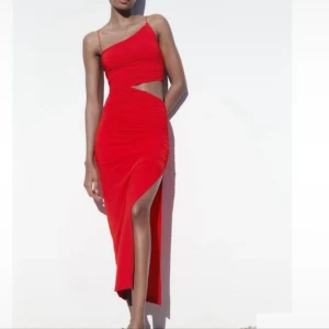 Röd oneshoulder klänning med slits - Säljer en snygg röd oneshoulder klänning med cut-out detalj i midjan och hög slits framtill. Klänningen har en figurnära passform och är perfekt för dig som vill sticka ut. 