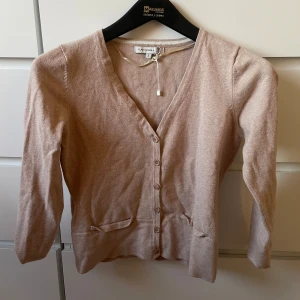 Beige kofta från Flash Woman - Säljer en beige kofta från Flash Woman i storlek S. Koftan har v-ringning, långa ärmar och knappar framtill. Den är jättebekväm och den har jätte bra passform!