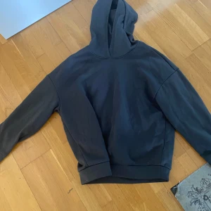 Svart hoodie med tryck - Säljer en svart hoodie med huva och tryck på ryggen där det står 'NOTHING' och 'ALL THINGS COME TO THOSE WHO WAIT'. Hoodien har en avslappnad passform och är perfekt för en chill stil.