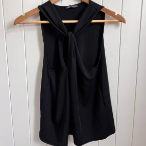 Svart ärmlös topp med knyt från Zara - Snygg svart ärmlös topp från Zara med knyt framtill vid halsen