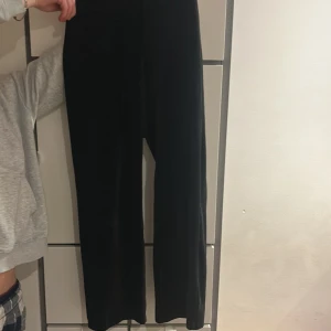 Svarta byxor i velour från Lindex - Mysiga svarta byxor i velour från Lindex med normal passform och raka ben. Byxorna har snörning i midjan för extra komfort och stil. Perfekta för en avslappnad look.