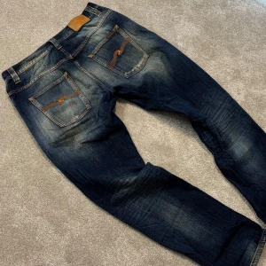 Nudie jeans - Tja! Säljer dessa riktigt feta blå Nudie jeans med stört najs tvätt och lite feta slitningar på benet! Jeansen är utav modellen ”Hank Rey” och har en straight passform. Size 33/32 men sitter som 32/32. Skriv vid funderingar!
