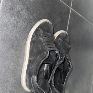 Svarta sneakers från Axel arigato - Säljer ett par svarta sneakers med vit platt sula från Axel arigato. Skorna är rätt så använda men inga hål eller något som gör de oanvända. Pris kan diskuteras och skriv om det behövs mer bilder. Köpt för ca 2000 originalpris. 