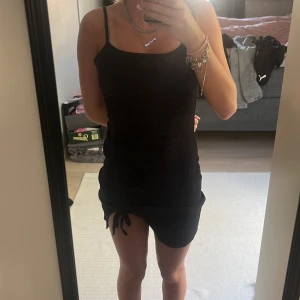 Svart kortklänning  - Svart tight ribbad klänning från SHEIN med smala axelband och knytning i sidan. Kort modell som sitter snyggt på kroppen och passar perfekt till sommaren.