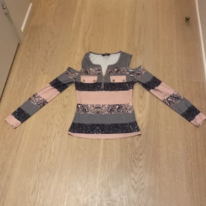 Randig långärmad topp med axelcutouts från ChicMe - Säljer en långärmad topp från ChicMe i storlek S. Tröjan har breda ränder i rosa, grått och svart med mönster, axelcutouts och dragkedja framtill. Två dekorativa fickor på bröstet. Perfekt för dig som gillar unika detaljer! Helt oanvändbar och köpt 16 Maj!