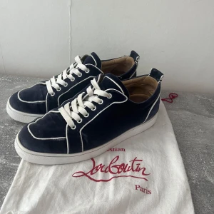 Christian Louboutin skor mörkblå/vit - Christian Louboutin skor mörkblå/vit i använt skick, repaintade under och liten skada på bild 5, även lite sliten inuti vid hälen på ena skon. Dustbag ingår. 