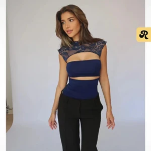 Mörkblå croppad topp med spetsdetaljer - Säljer en mörkblå croppad topp Toppen har ärmlös design och en snygg cut-out detalj framtill.  Skriv ifall ni har frågor ❤️