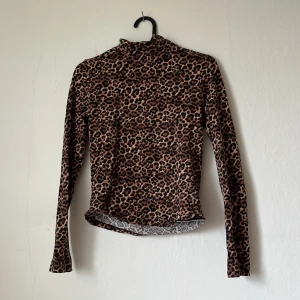 Leopardmönstrad polotröja från Monki - Säljer en leopardmönstrad polotröja från Monki i storlek S. Tröjan har lång ärm och är tillverkad i ett mjukt, stretchigt material. Perfekt för dig som vill sticka ut lite extra med ett djurmönster.