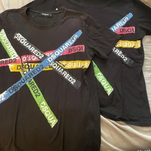 Svart t-shirt från Dsquared2 med färgglatt tryck - Cool svart t-shirt från Dsquared2 med stort färgglatt X-tryck över bröstet i blått, grönt, rött och gult. Rund halsringning och normal passform. Perfekt för dig som gillar streetwear och vill sticka ut.Köpt för 2500/st XL XXL