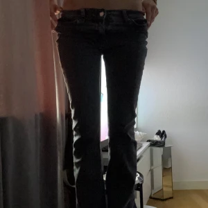 Gråa bootcut jeans - Säljer ett par gråa jeans med bootcut-modell och låg midja. Klassisk femficksdesign och knappgylf. Perfekta för dig som gillar en tidlös och enkel stil.