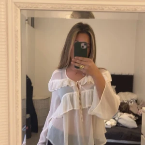 Vit genomskinlig blus  - Luftig tyg med volanger runt om brösten och axlarna. Jättefin men ingen vill inte visa så mycket. Men perfekt med en bikini under 