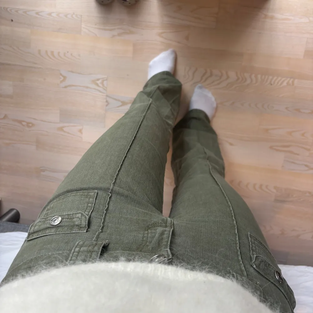 Snygga olivgröna cargopants med raka ben och dekorativa fickor framtill med knappar. Byxorna har normal passform och är perfekta för en avslappnad stil. . Farkut & Housut.