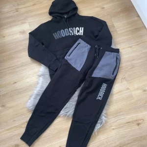 Svarta mjukisbyxor från Hoodrich med grå detaljer - Säljer ett par svarta mjukisbyxor från Hoodrich med grå paneler vid fickorna och vit logga på benet. Byxorna har snörning i midjan och dragkedjor vid fickorna. Perfekta för en avslappnad stil.