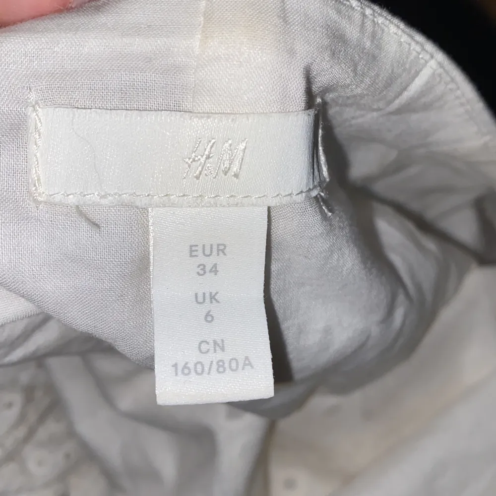 Superfin vit blus från H&M med broderade detaljer och stora puffärmar. Blusen är axelbandslös och har ett romantiskt hålmönster i tyget. Perfekt för vår och sommar!. Yläosat.