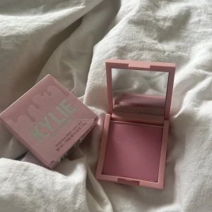 Kylie Cosmetics Pressed Blush Powder 'Winter Kissed' - Rosa pressat rouge från Kylie Cosmetics i nyansen 'Winter Kissed'. Kommer i en söt ljusrosa förpackning med spegel i locket. Perfekt för att ge kinderna en fräsch och naturlig färg.