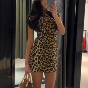 Leopardmönstrad ärmlös kortklänning - Säljer en snygg ärmlös kortklänning med leopardmönster. Klänningen har en rak passform och hög hals, perfekt för dig som vill sticka ut. Materialet känns mjukt och följsamt mot kroppen.