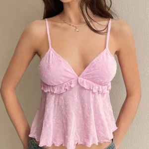 Linnetopp 💗 - Supersöt ljusrosa linnetopp med tunna axelband och blommigt mönster. Toppen har volangdetalj under bysten och en lätt utsvängd, flowy passform. Perfekt för varma dagar och ger en romantisk vibe.
