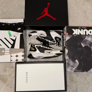 Nike Zoom 2K sneakers svart/vit - Nike Zoom 2K sneakers i svart och vitt med tydlig Zoom-logga på sidan och klassisk Nike-logga på plösen. Skorna har en sportig design med snörning och rund tå. Ovandelen är i syntetmaterial och mesh för bra andningsförmåga.