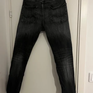 Svarta slim jeans med slitningar - Säljer ett par svarta jeans med slitningar från Jack & Jones .