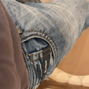 Blå jeansbyxor från Blend 30/32 - Säljer ett par klassiska blå jeans från Blend med normal passform. Jeansen har raka ben, fem fickor och tydliga slitningar för en avslappnad look. Perfekta till vardags och passar till det mesta. Snygga detaljer på bakfickorna.