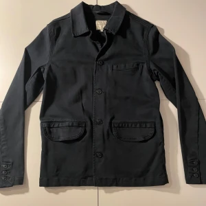 Marinblå overshirt från Selected - Snygg marinblå overshirt från Selected med knappar framtill och klassisk krage. Den har två framfickor och en bröstficka, perfekt för en stilren look.