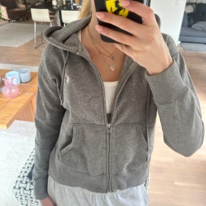 Grå zip-hoodie från Ralph Lauren - Säljer en grå hoodie från Ralph Lauren med dragkedja och huva. Tröjan har två fickor framtill och den klassiska broderade loggan på bröstet. 