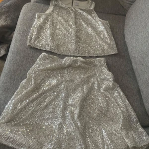 Glittrig silverkjol - Säljer en glittrig silverfärgad kjol med paljetter. Kjolen har en kort modell och är perfekt för dig som vill sticka ut. Matcha med en enkel topp eller kör all in med matchande paljettlinne.