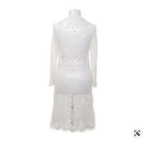 Vit virkad klänning - Charmig vit virkad klänning med lång ärm och offshoulder-design. Klänningen har ett vackert mönster och knytning vid halsen. Perfekt för en bohemisk look.