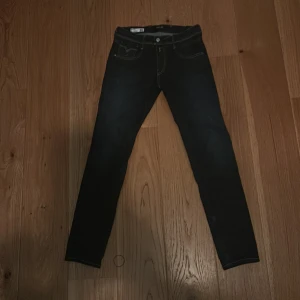 Mörkblå Replay jeansbyxor - Säljer ett par mörkblå jeans från Replay med klassisk femficksdesign och snygga kontrastsömmar. Byxorna har raka ben och bakfickor med dekorativa sömmar. Perfekta för dig som gillar stilrena jeans med bra passform.