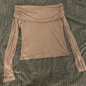Beige offshoulder topp från NLY Trend - Säljer en beige offshoulder topp från NLY Trend i mjukt och tunt material. Toppen har långa ärmar och en bred, draperad krage som ger en snygg och trendig look. Perfekt att styla med jeans eller kjol!