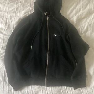 Svart hoodie med dragkedja från H&M - Säljer en svart hoodie från H&M i storlek M. Tröjan har huva, dragsko och hel dragkedja framtill samt två fickor. Perfekt för en avslappnad stil. Jätte skön inuti, knappt använd. ( tvättar innan jag skickar)
