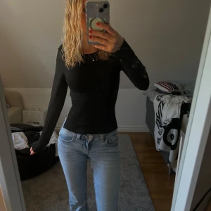 Svart långärmad topp med öppen rygg - Säljer en svart långärmad topp med tight passform och öppen rygg som knyts med snörning. Perfekt för dig som vill ha en stilren men ändå unik look. Tunn och stretchig, passar till både jeans och kjol. Snygg detalj med öppen rygg och knytband. Använt 1-2 gånger. 