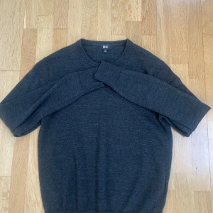 Mörkgrå marinull tröja från Uniqlo - Mörkgrå stickad tröja från Uniqlo i storlek XS. Klassisk rund halsringning och långa ärmar. Enkel och stilren design som funkar till det mesta. Mjuk och skön känsla, perfekt för kyligare dagar.
