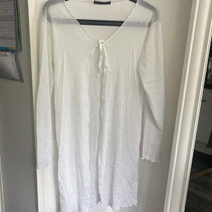 Vit långärmad strandklänning Vero Moda - Superfin vit långärmad strandklänning från Vero Moda. Klänningen har v-ringning med knyt framtill och lätt vågiga kanter nertill. Perfekt för sommarens varma dagar eller som strandplagg.❤️jag vet inte riktigt storleken men skulle tro M.