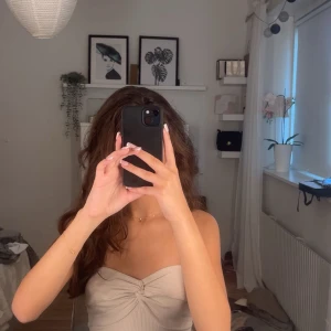 Beige bandeau tubtopp med twist - Säljer dessa två tub toppar den första har en twistdetal framtill och den andra har slits på sidorna. Topparna är ribbade och sitter tight, perfekt för dig som gillar en enkel men trendig look. Ärmlös och axelbandslös modell som passar till jeans eller kjol. Aldrig använt de!