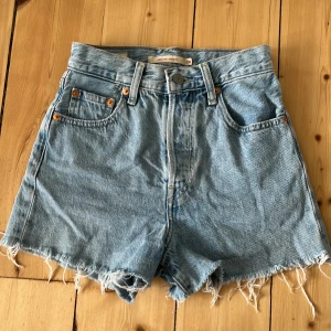 Levi’s shorts i modellen Ribcage shorts  - Shortsen är använda ett få tal gånger men det finns inga defekter så som fläckar eller hål. Shortsen är högmidjade och midjemåttet rakt över är 30 cm.