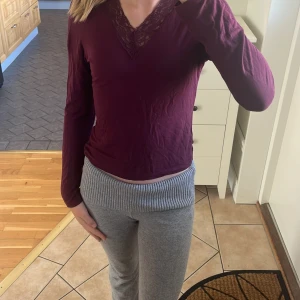 Vinröd långärmad topp med spets Gina Tricot - Vinröd långärmad topp från Gina Tricot med snygg v-ringning och spetsdetaljer framtill. Mjuk och skön i bomullsmaterial, perfekt för dig som gillar en enkel men ändå feminin stil. Passar till både jeans och kjol.