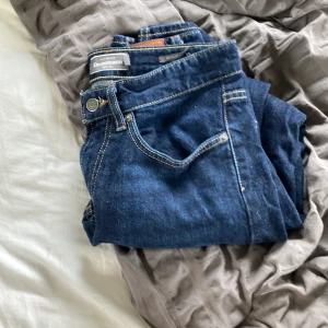 Mörkblå jeans från Dressmann Regular Fit - Snygga mörkblå jeans från Dressmann i modellen Regular Fit. Klassisk femficksdesign med kontrastsömmar och rak passform. Perfekta till vardags och lätta att matcha med olika stilar. Tillverkade i slitstarkt denimtyg.