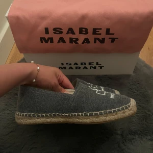 Grå espadrillos från Isabel Marant - Snygga grå espadrillos från Isabel Marant med broderad logga framtill. Ovandel i textil med naturfärgad sula i flätad jute och gummidetaljer undertill. Perfekta för en chill och trendig look under varmare dagar. Helt nya, inte använt en enda gång de dem var för små och kan inte skicka tillbaka dem🫶🏼 pris diskuteras vid snabb försäljning🙏