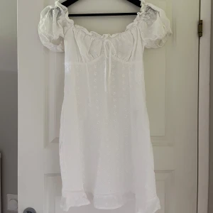 Vit klänning från Nelly - Superfin vit kort klänning från Nelly med broderade blommor, puffärmar och söt snörning framtill. Köpte till min student men valde en annan