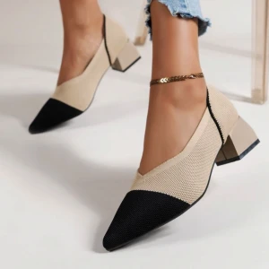 Beige och svarta pumps med klack - Stilrena pumps i beige med svart tå och markerad spetsig tå. Skorna har en låg, bred klack och är tillverkade i ett stickat syntetmaterial som ger en modern känsla. Perfekta för dig som vill ha en trendig och bekväm sko med snygg kontrast.