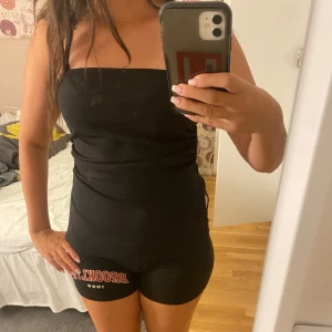 Svart kort klänning från 157 - Säljer en svart, tight och kort klänning från 157 med axelbandslös design och en snygg slits på sidan. Klänningen har en clean look och sitter figurnära, perfekt för dig som gillar minimalistisk stil. Materialet känns mjukt och stretchigt mot kroppen.