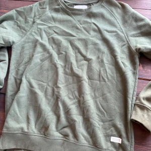 Olivgrön sweatshirt från 157, M - Enkel och stilren olivgrön sweatshirt från 157 i storlek M. Tröjan har rund halsringning, långa ärmar och mjukt material som känns skönt mot huden. Perfekt för en avslappnad look och funkar året runt.