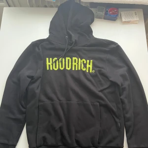 Svart HOODRICH hoodie XL med gul text - Svart hoodie från HOODRICH i storlek XL men sitter som L