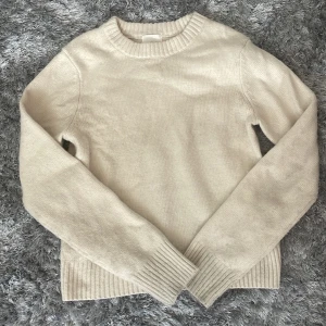 Beige stickad tröja från H&M XS - Säljer en enkel och snygg beige stickad tröja från H&M i storlek XS. Tröjan har rund hals, långa ärmar och breda ribbade muddar vid ärmslut och nederkant. Perfekt för att hålla sig varm. Säljer då den är för liten💗